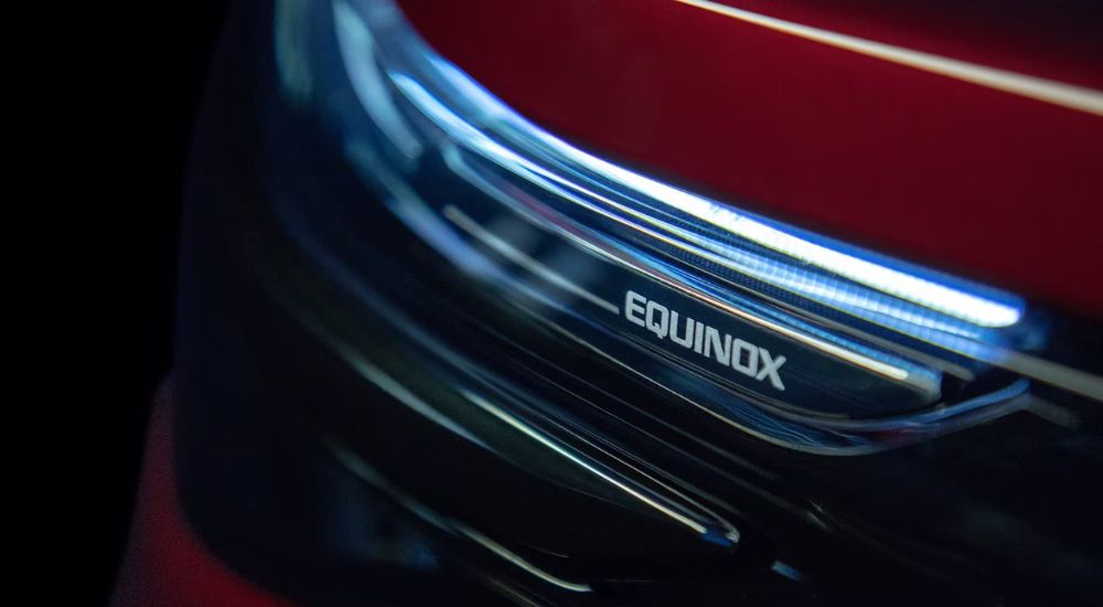 A close up shows the 'Equinox' badge on a red 2024 Chevy Equinox RS.