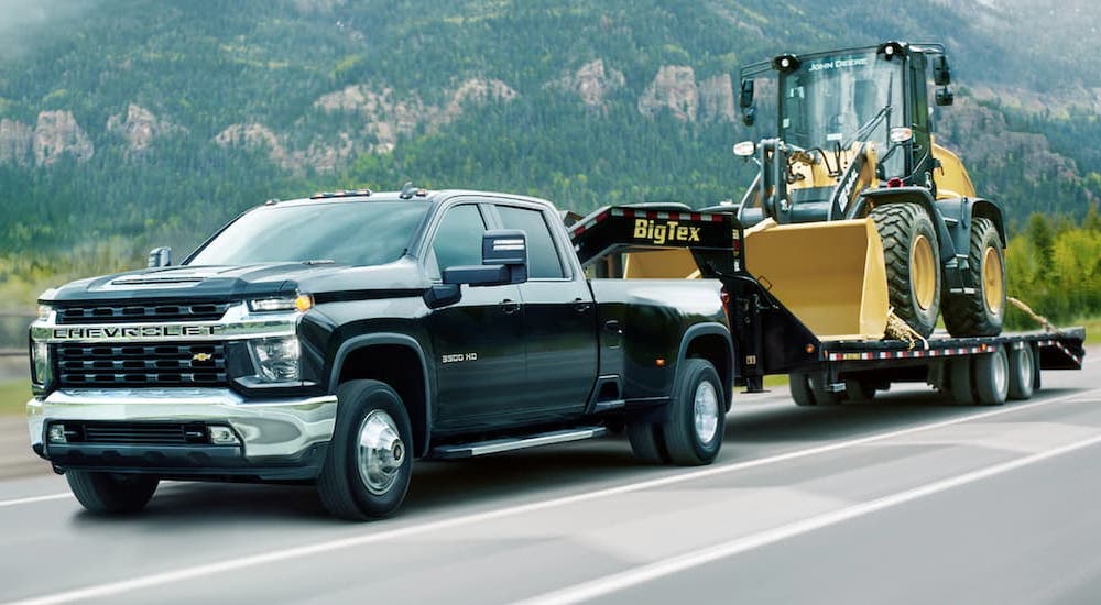 A black 2021 Chevy Silverado 3500HD is shown towing a bulldozer.