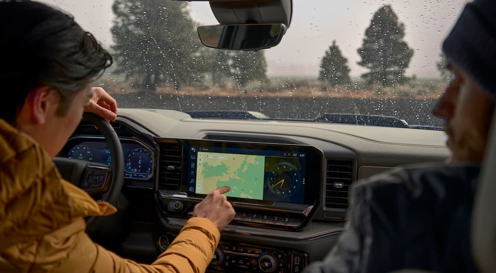 A woman using the infontainment screen in the black interior cabin of a 2025 Chevy Silverado 1500.