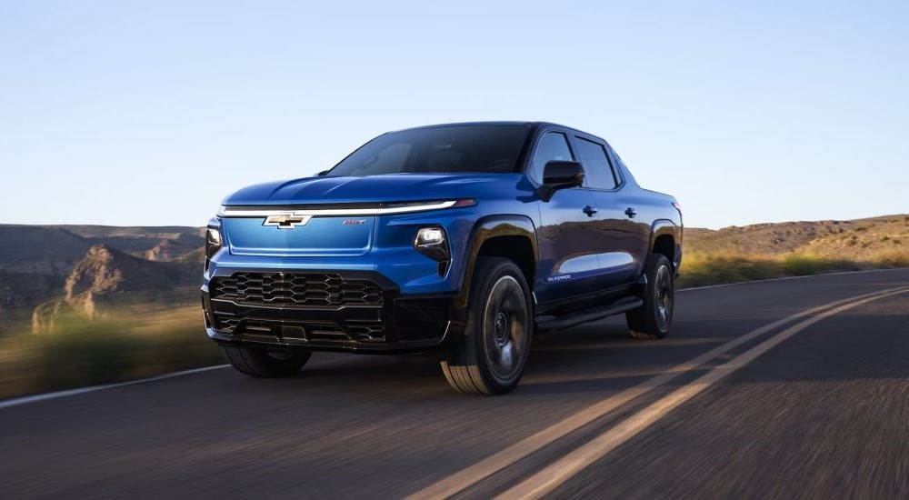 A blue 2025 Chevy Silverado EV RST driving down a road.