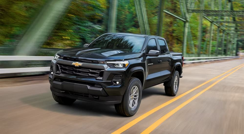 A black 2023 Chevy Colorado driving to a used car dealer.