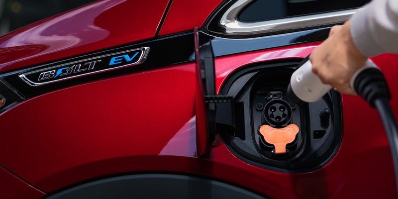 A red Chevy Bolt EV being plugged in.