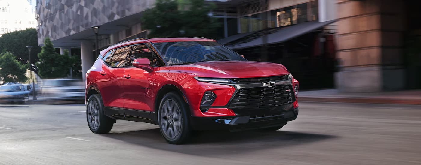Red 2026 Chevy Blazer driving down a city street.