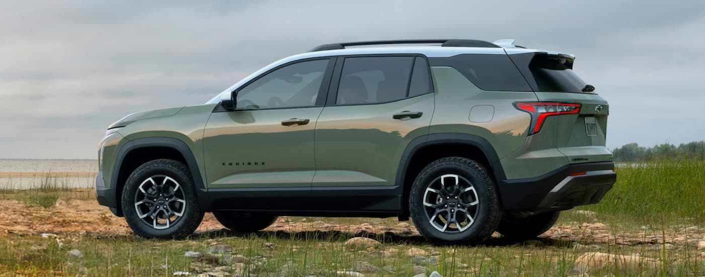 Side of a green 2027 Chevy Equinox parked off-road.