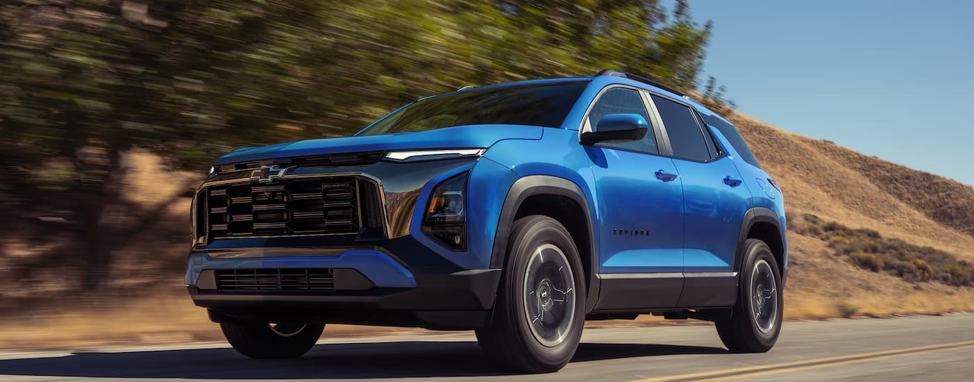 Blue 2027 Chevy Equinox driving down a road.