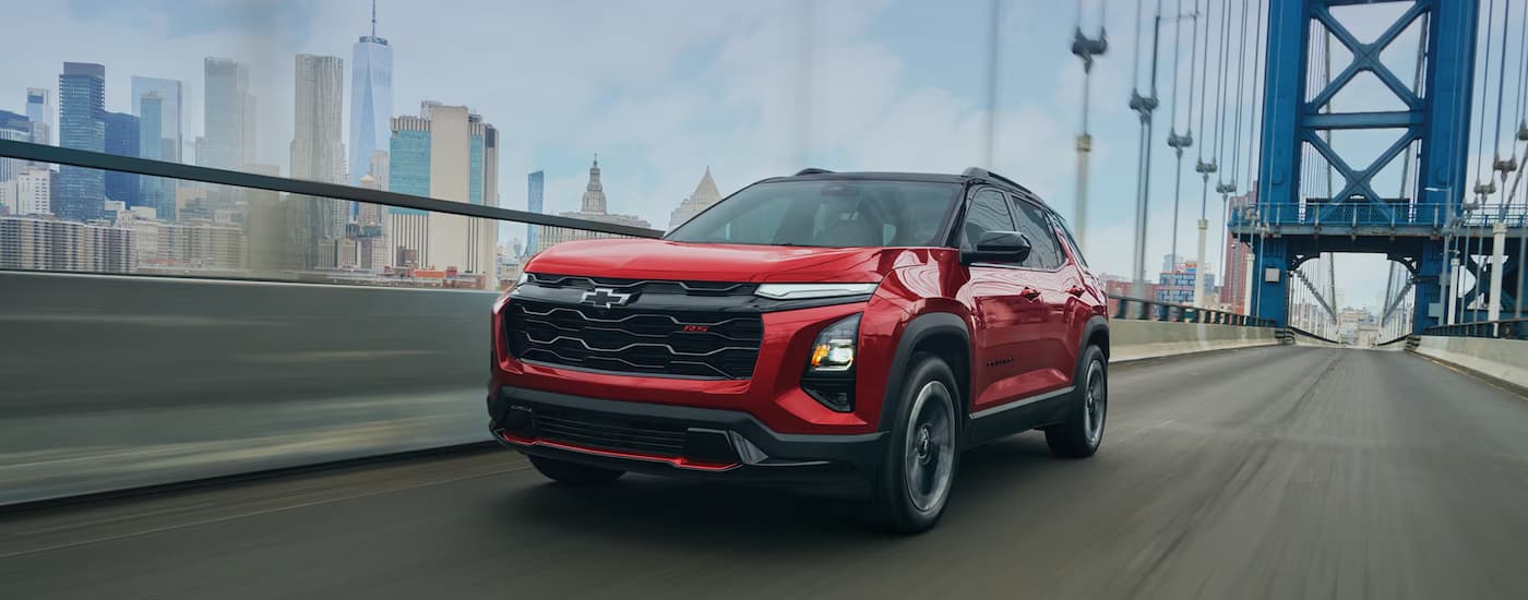 Red 2027 Chevy Equinox driving across a bridge.