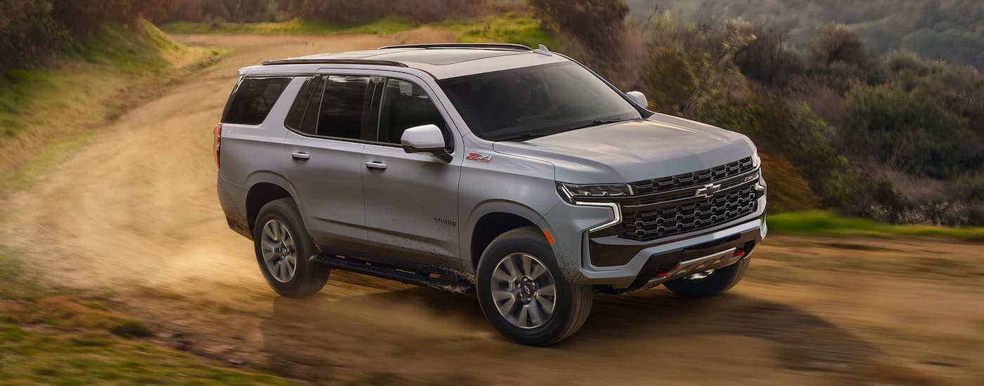 A silver 2024 Chevy Tahoe Z71 driving around a dirt bend.