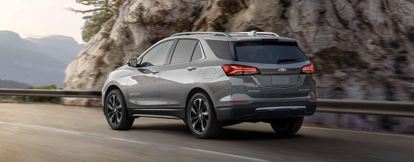 A silver 2023 Chevy Equinox LT is shown driving near a mountain.