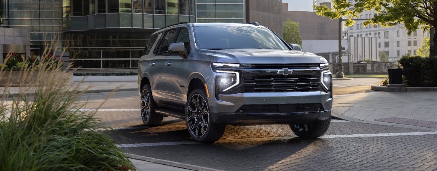 A silver 2025 Chevy Tahoe RST driving through the city to a Chevy dealer near Westland.