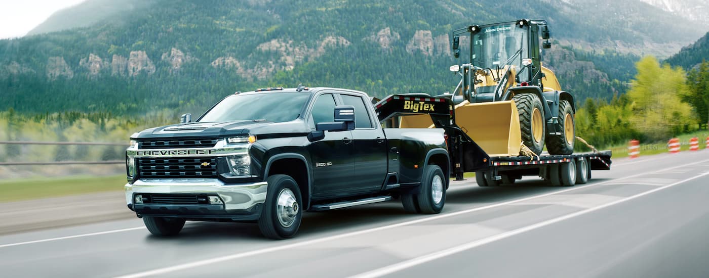 A black 2021 Chevy Silverado 3500HD is shown towing a bulldozer.