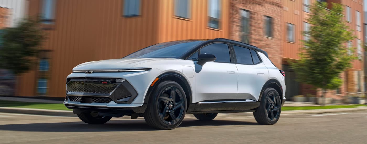 White 2025 Chevy Equinox EV driving through a city.