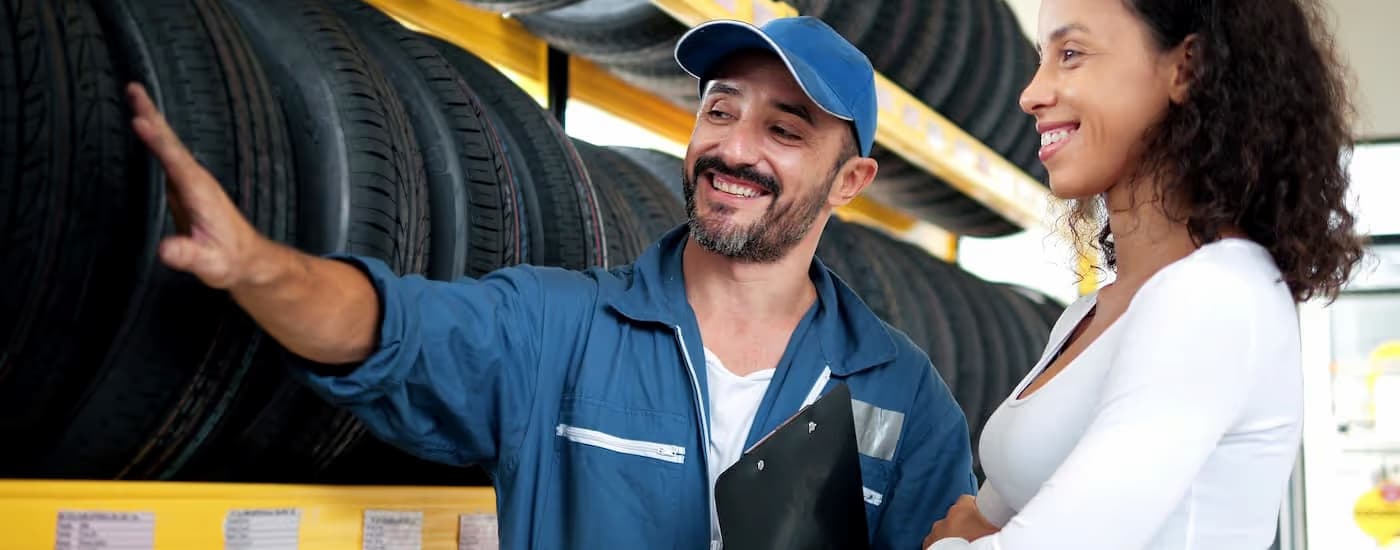 Mechanic showing a customer to a row of tires.