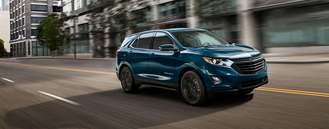 Dark green 2021 Chevy Equinox driving from a used car dealer in Plymouth.