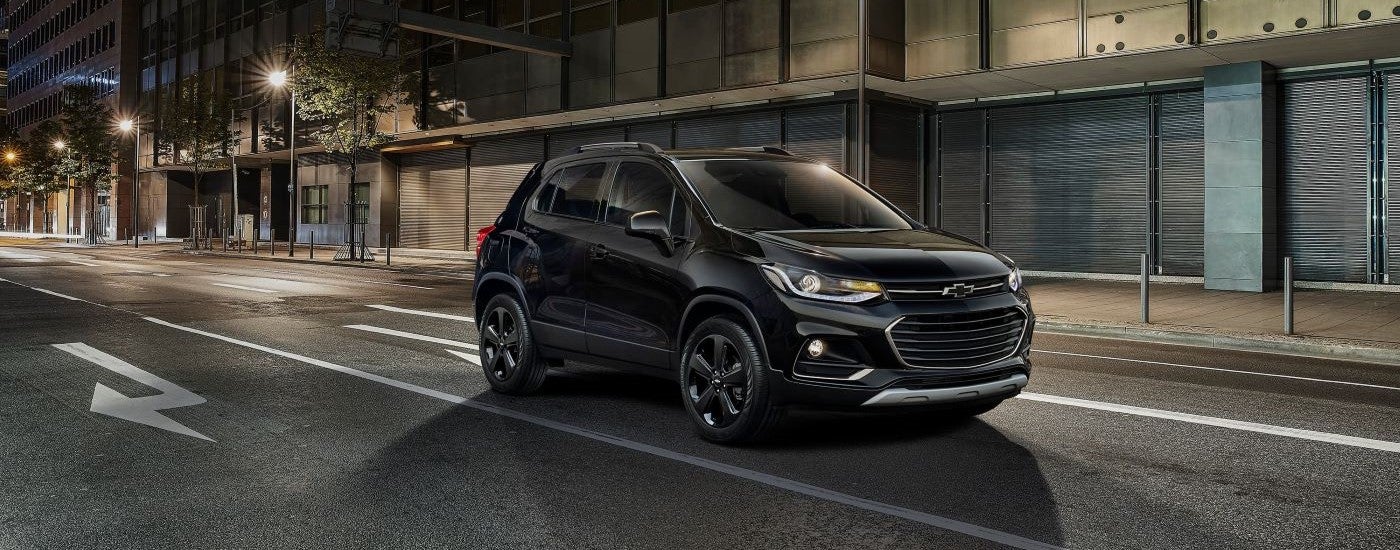 A black 2018 Chevy Trax driving from a used Chevy dealer.