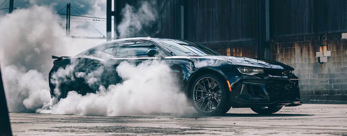 A black 2022 Chevy Camaro performing a burnout.