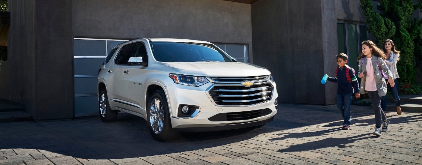 A white 2019 Chevy Traverse is shown parked near a garage.