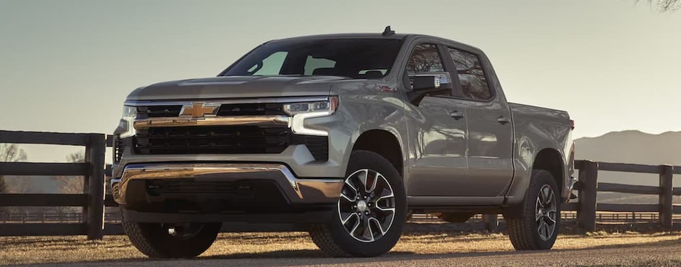 A silver 2026 Chevy Silverado 1500 parked off-road from a car dealership