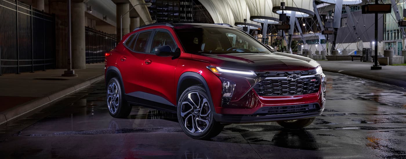 A red 2025 Chevy Trax RS parked in a city at night