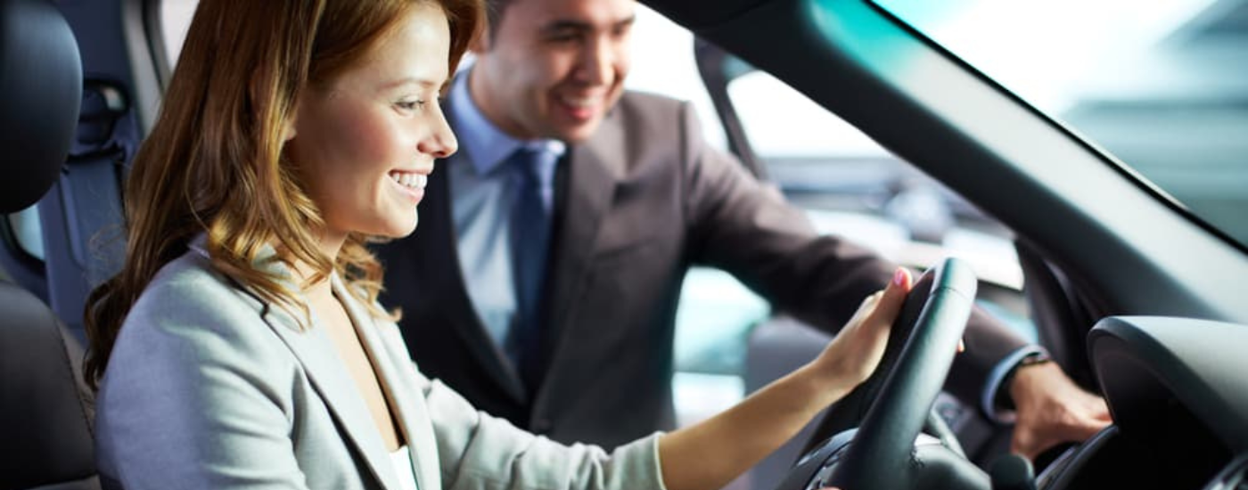 A woman sitting in a car talking to a salesman
